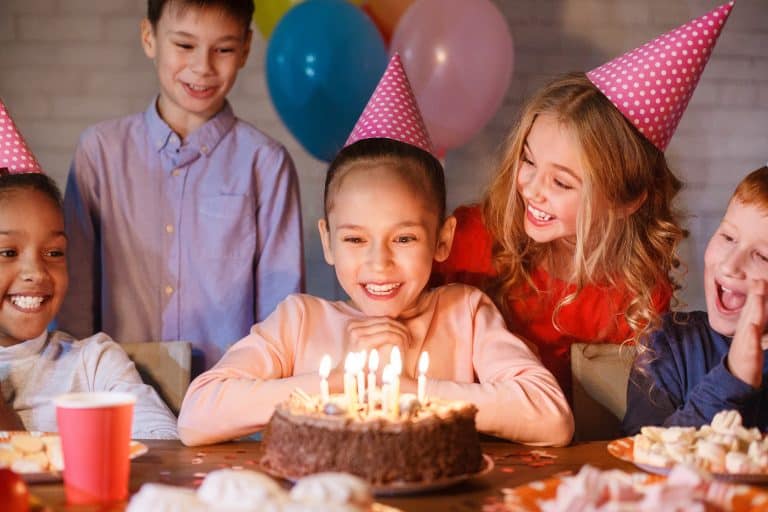 Girl looking at birthday cake with candles, having b-day party